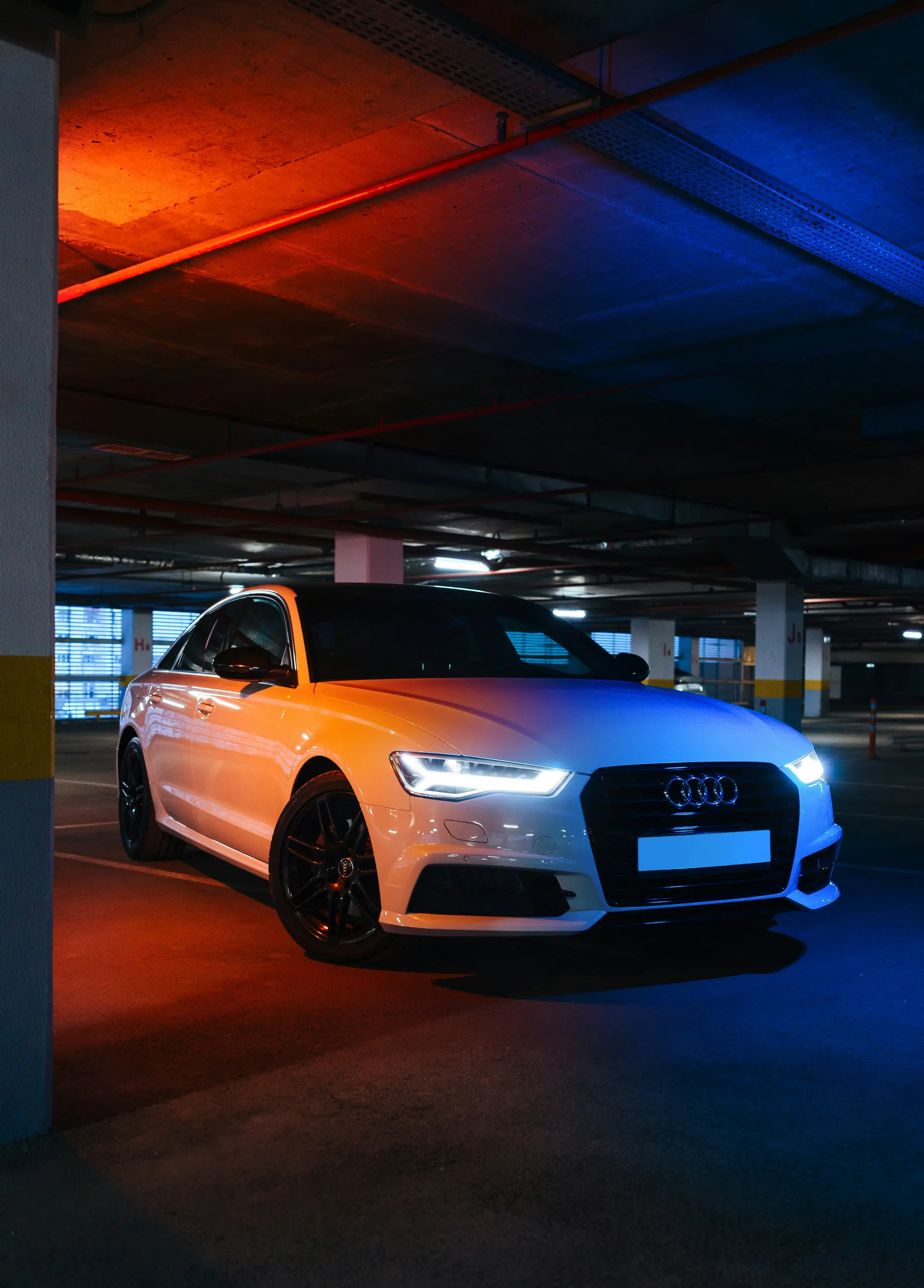 Audi A6 blanco en un aparcamiento subterráneo con iluminación de neón